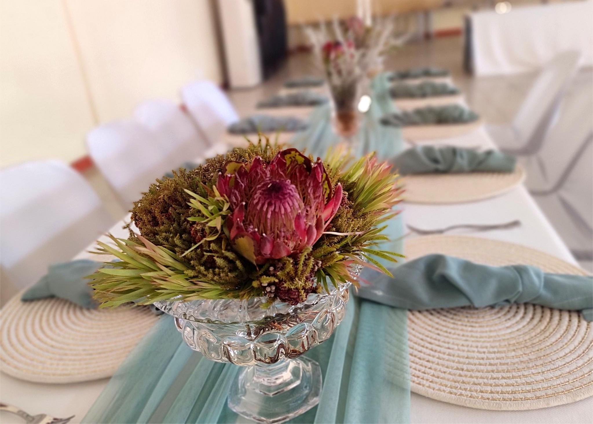 A beautifully decorated table with protea in a glass
